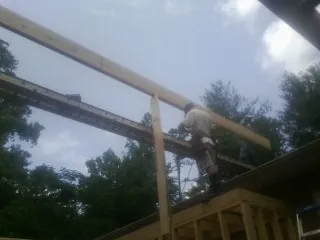 Carpenter setting a ridge beam over a new addition frame — Ice Dam Removal by Roofing Brothers in Mcclusky