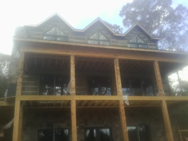 Dormers and porch framing on a large log home under construction — Roof Coating work by our crew in Mcclusky