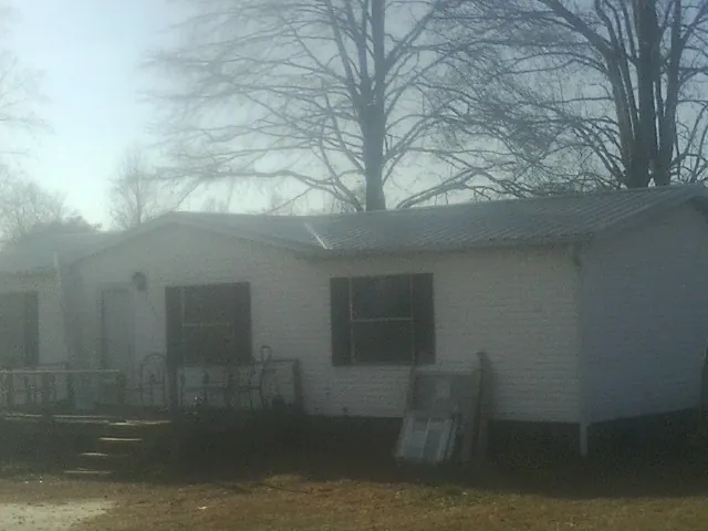 New metal roof on a white painted brick home on a foggy morning in Mcclusky
