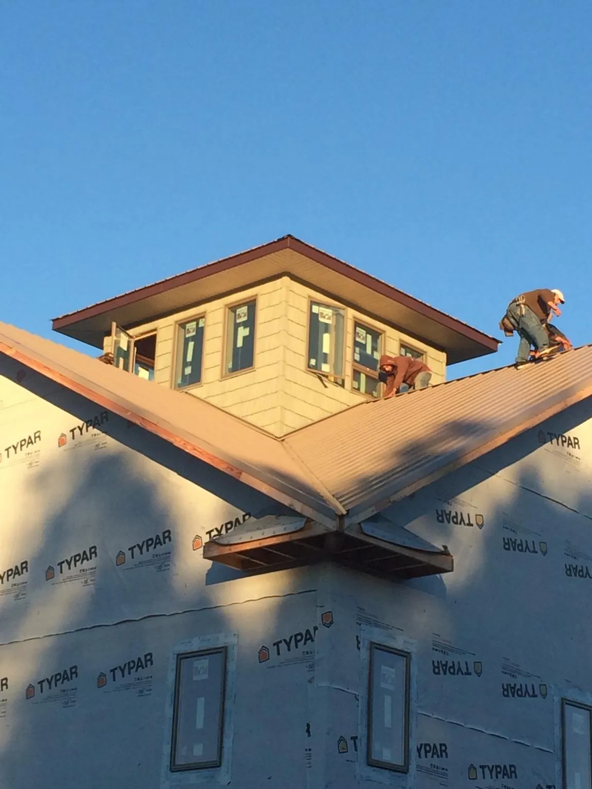 Roofers working around a rooftop cupola on a new metal roof at sunset — Roof Waterproofing in Mcclusky by Roofing Brothers
